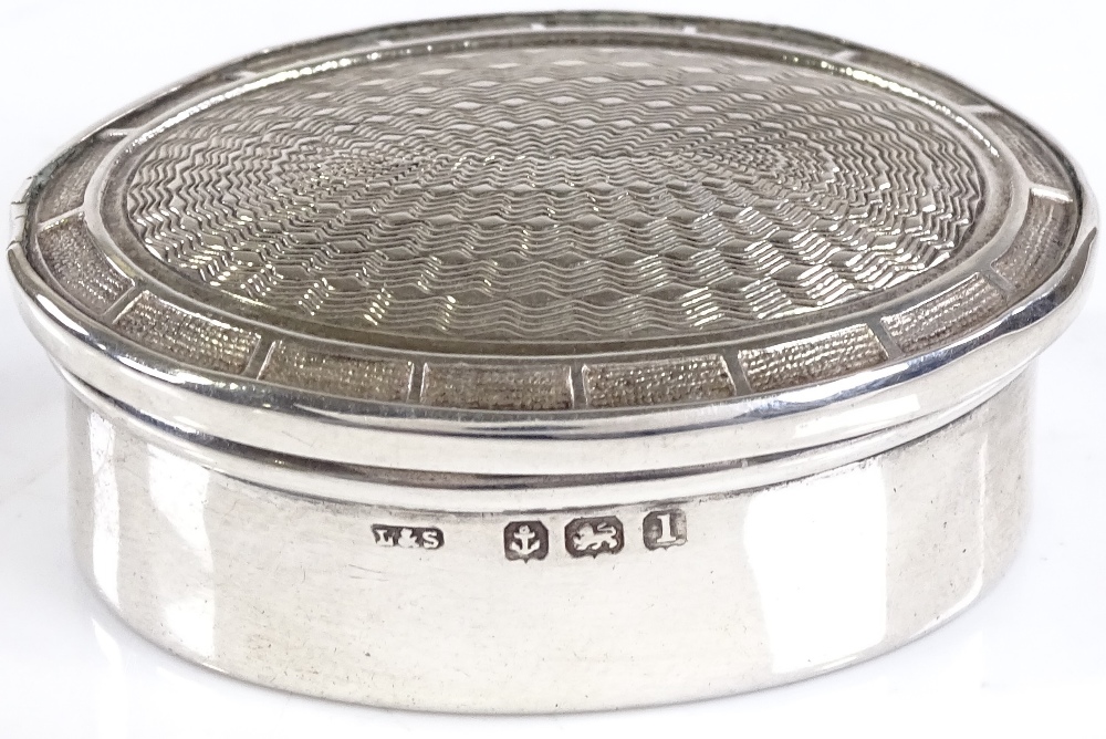 An oval silver pillbox, with engine turned lid, by Levi & Salaman, hallmarks Birmingham 1910, length