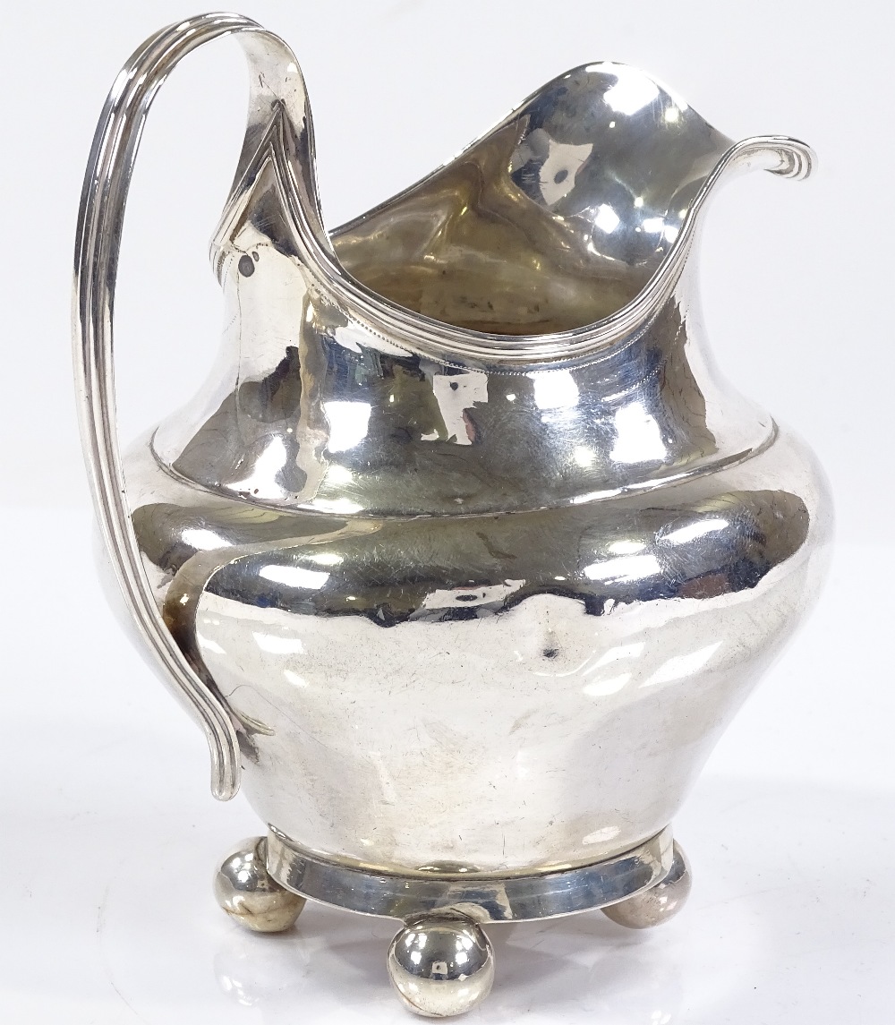 A silver bulbous cream jug, with reeded handle and bun feet, indistinct hallmarks, height 12cm, 4oz - Image 2 of 3