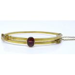 An unmarked gold garnet and diamond hinged bangle, with cannetille tips, internal diameter 56.7mm,