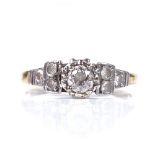 An unmarked gold solitaire diamond dress ring, with diamond set shoulders, central stone approx 0.