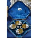 A set of 4 silver plated shell design salts with matching spoons, in fitted case