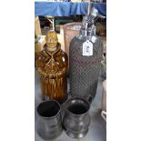 A mesh-covered soda syphon and a monk figure Whiskey decanter