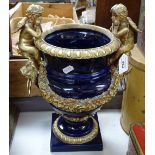 An ornate ceramic and brass-mounted urn with cherub mounts, overall height 14"