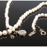 A graduated single standard long strand pearl necklace, on unmarked gold diamond set flowerhead