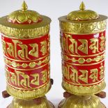 A pair of large ornate Tibetan relief embossed painted and gilded metal prayer wheels, height