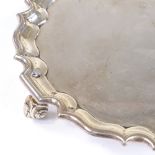 A circular silver salver / card tray, with scalloped edge and scrolled acanthus leaf feet, by Thomas