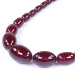 A string of graduated cherry amber beads, on silver clasp, largest bead length 32.2mm, necklace