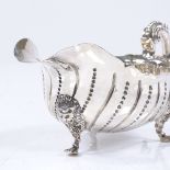 A late Victorian silver gravy boat, with intaglio fluted decoration and lion mask feet, by John