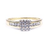 An 18ct gold diamond cluster ring, with channel set diamond shoulders, total diamond content
