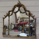 An ornate gilt-gesso framed triple glass over-mantel mirror, probably early 20th century, with bevel