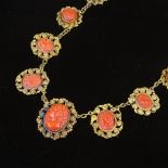An Antique unmarked gold 15-panel carved coral necklace, with closed back, relief carved Classical