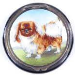 A circular silver and enamel powder compact, with Pekingese dog decorated lid and mirror interior,