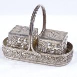 An unmarked white metal miniature cruet set, with relief embossed wheatsheaf decoration, basket