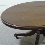 A 19th century oval mahogany tilt-top dining table, on carved quadruple base