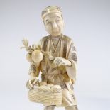 A Japanese Meiji period sectional carved ivory figure of a farmer carrying fruit, carved hardwood