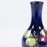 A Moorcroft Pottery plum design blue ground narrow-neck vase, painted signature, height 23cm