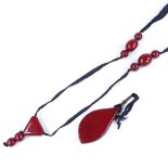 A long cherry amber bead pendant necklace, on silk thread, pendant height 66.4mm, 35.8g total (A/F)