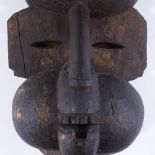 An African Ibibio carved and stained wood Tribal mask, in the form of a cooking pot above a baboon's