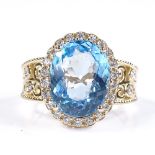 A 14ct gold blue topaz and diamond halo cluster ring, with diamond set pierced shoulders, oval-cut