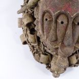 An African carved and painted wood Tribal fetish mask, with monkey skull mount, height 43cm