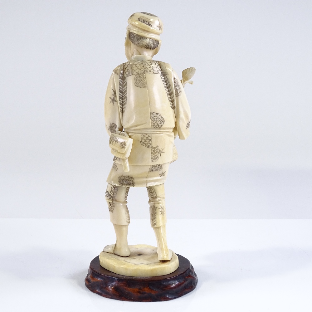 A Japanese Meiji period sectional carved ivory figure of a farmer carrying fruit, carved hardwood - Image 3 of 4