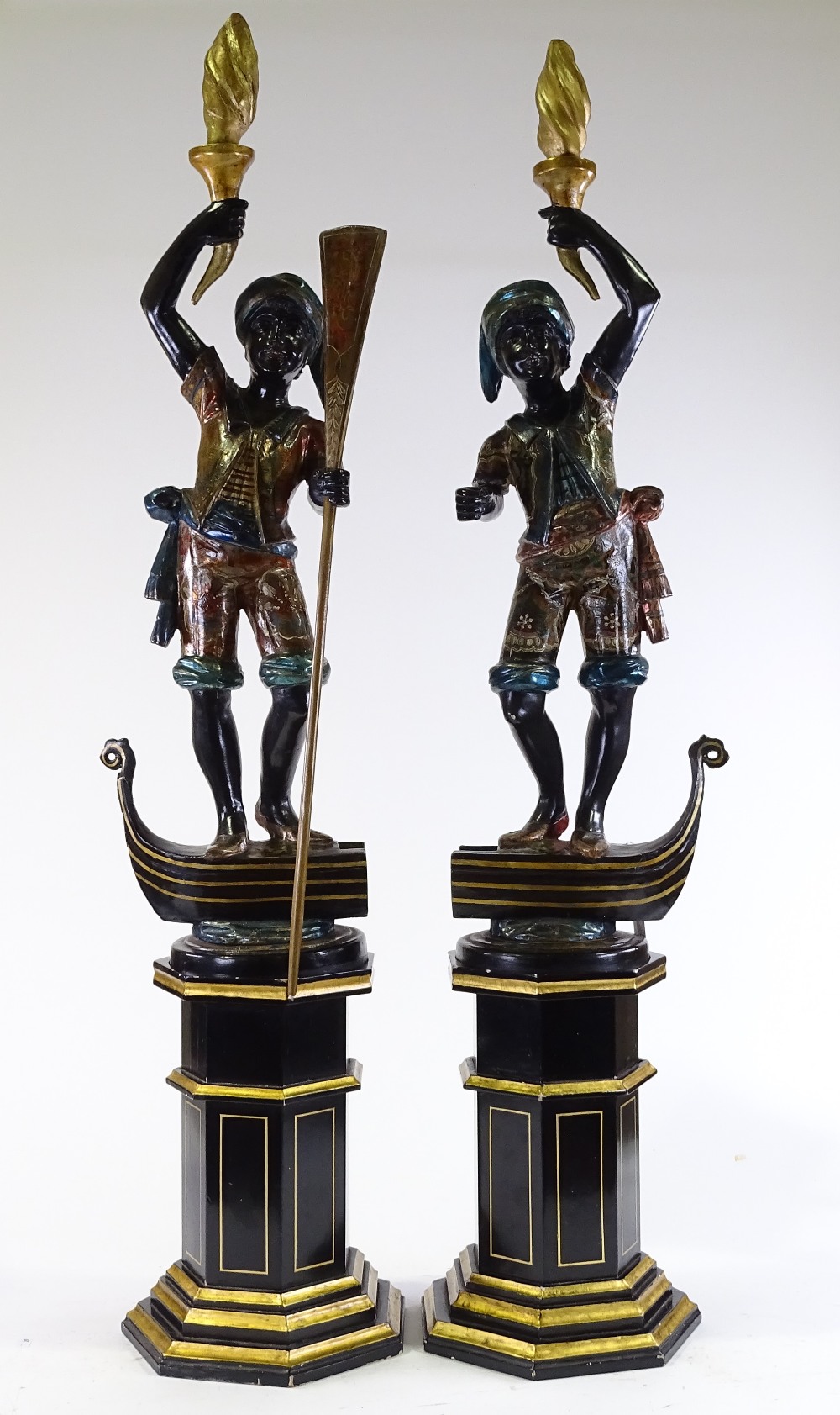 A pair of Italian carved and painted wood gondolier torchere figures, on gilded octagonal pedestals,