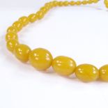 A graduated string of pale amber beads, largest bead length 27.5mm, necklace length 70cm, 104.6g