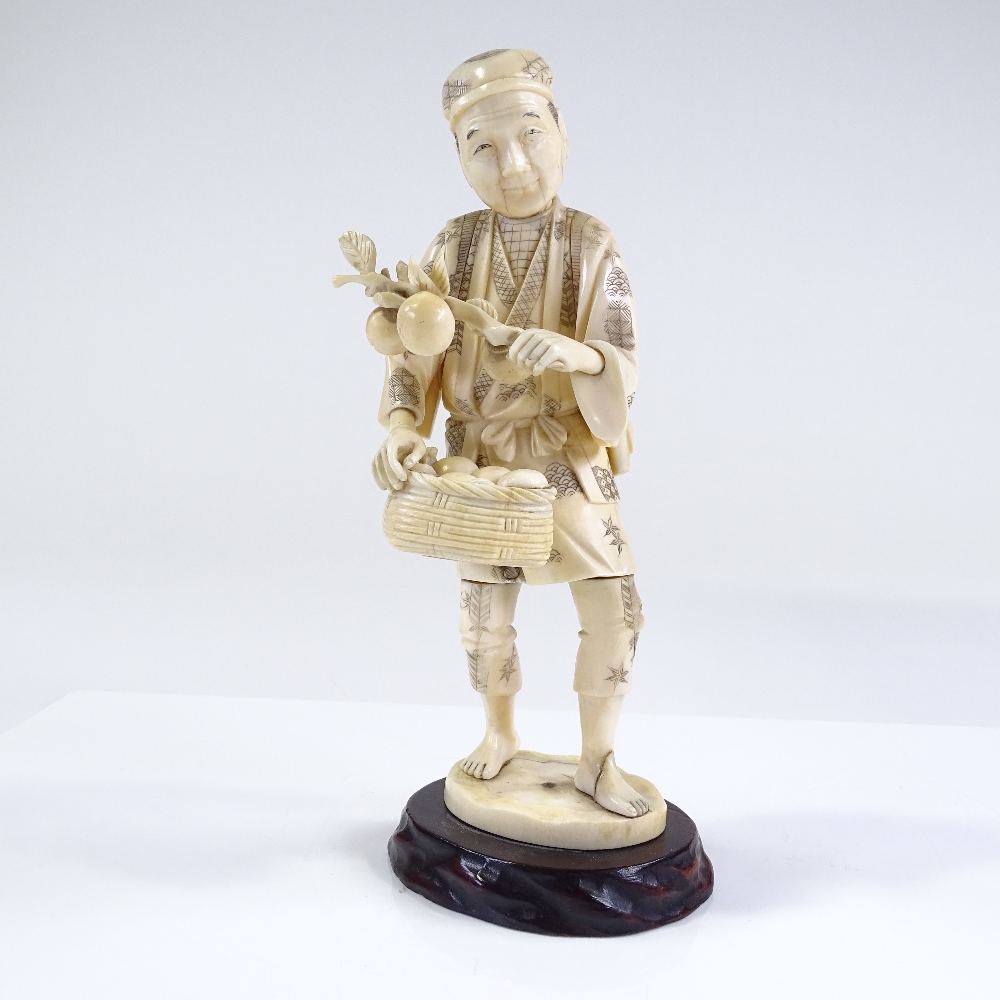 A Japanese Meiji period sectional carved ivory figure of a farmer carrying fruit, carved hardwood - Image 2 of 4