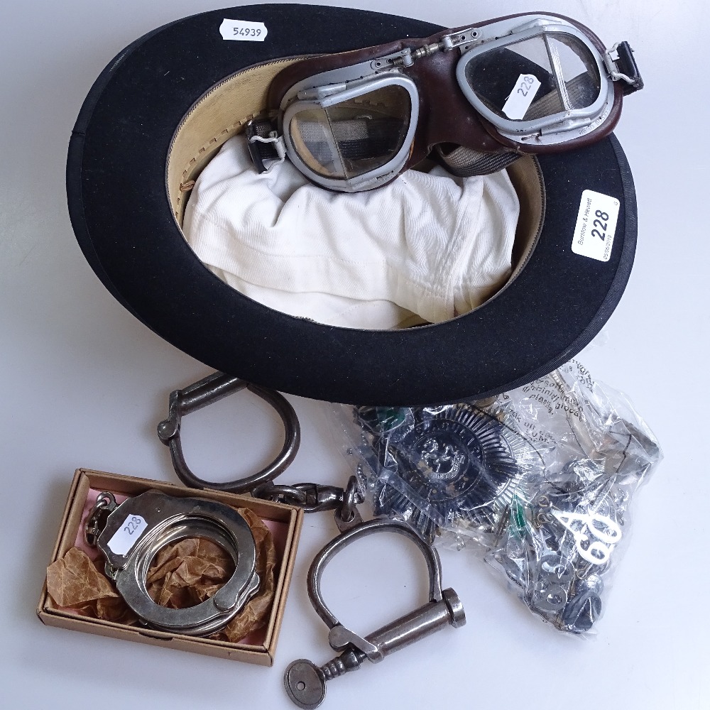 A Lock & Co bowler hat, goggles, police badges, handcuffs etc