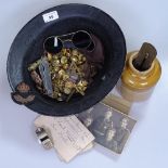 An Army helmet containing military items, including goggles, buttons, badges, stone jar and