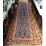 A red ground Persian design runner with symmetrical pattern, 400cm x 105cm