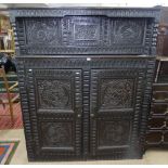 A large Antique oak 2-section cupboard, with all over chip carved decoration and panelled doors,