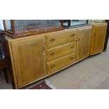 An Ercol light elm low sideboard, with fitted drawers and cupboards, and a matching single door