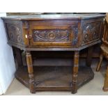 A 1920s oak console table, with canted corner and single carved panel door, raised on turned legs,