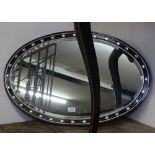 An ebonised oval bevelled-edge wall mirror, L79cm