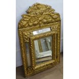 A Continental embossed gilt-metal framed cushion wall mirror, W60cm, H94cm
