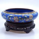A cloisonne bowl with floral decoration, 8" diameter, on carved wood stand