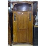 A stylised Art Nouveau oak hall cupboard, with single panel door and copper panels, on bracket feet,