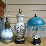 A blue and white oil lamp, a pierced table lamp, and another with fringed shade