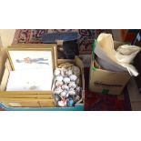 A box containing ceramic handles, military prints, a collection of books, and a monitor