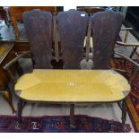 A 1920s French provincial settee, with 3 carved panelled back, rush-seated seat, on turned legs,