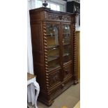 A late 19th century Continental carved oak and armorial 2-door bookcase, with glazed and carved