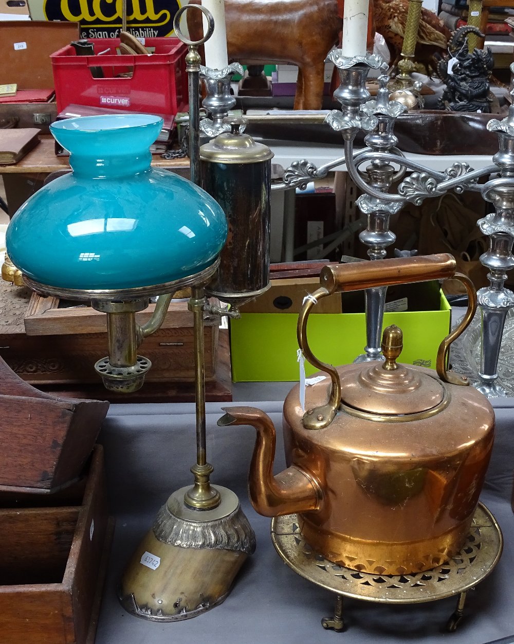 An adjustable brass oil desk lamp on horse's hoof base, copper kettle, and trivet