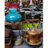 An adjustable brass oil desk lamp on horse's hoof base, copper kettle, and trivet