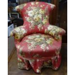 An Edwardian upholstered armchair, with shaped back on turned legs