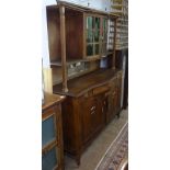 An Arts and Crafts oak dresser with green glazed cupboard doors, base fitted with bow-front frieze