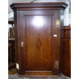 A George III oak hanging corner cupboard with single panelled door