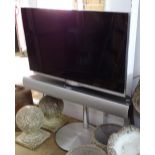 A Bang & Olufsen Beovision 7 television, and sound bar on fitted stand, complete with remotes,