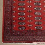 A red ground Turkemon design rug, 170cm x 130cm