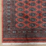 A salmon ground Turkemon design rug, 183cm x 123cmo